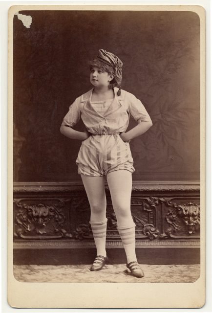 Full-length portrait of female facing front in short sailor-style costume, with knee-high stockings. Photo by Dr. Charles H. McCaghy Collection