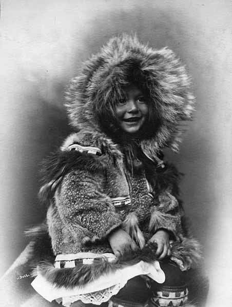 Inuit child sits for a studio portrait in her fur parka, Alaska, c. 1903