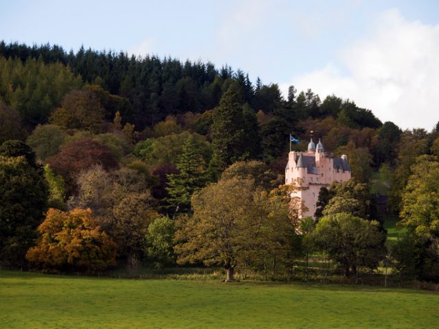 Craigievar Castle in Aberdeenshire, Scotland, surrounded by trees in autumn colors.
