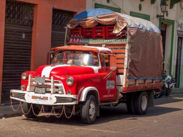 In Cartagena, Colombia – April 14, 2009: Red c. 1954 Dodge Stake truck stands by the side of the street being used for delivery of drinks in Cartagena’s old town.