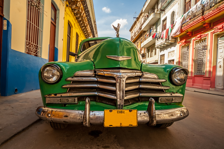 The cars match the colors of the buildings central Havana