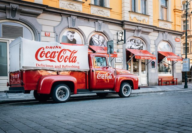 An old renovated 1934 Coca-Cola red delivery pickup truck. The Ford model is parked on a street in Prague, the Czech Republic in this picture.