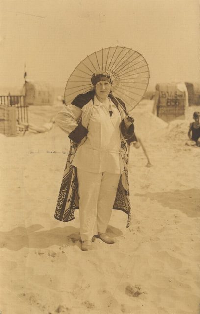A woman on the beach in 1905, toting an old-fashioned parasol.