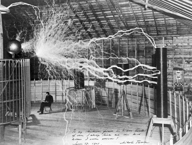 A multiple exposure picture of Tesla sitting next to his “magnifying transmitter” generating millions of volts. The 23 ft long arcs were not part of the normal operation, but only produced for effect by rapidly cycling the power switch.