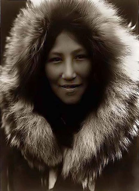 Ola, an Inuit girl with a gorgeous face peeking from her hood. Photographed by Edward S. Curtis.