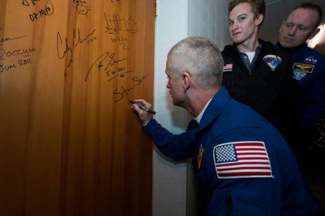 Expedition 39 Flight Engineer Steve Swanson of NASA performs the traditional door signing at the Cosmonaut Hotel prior to departing for launch in a Soyuz rocket. Photo by NASA.