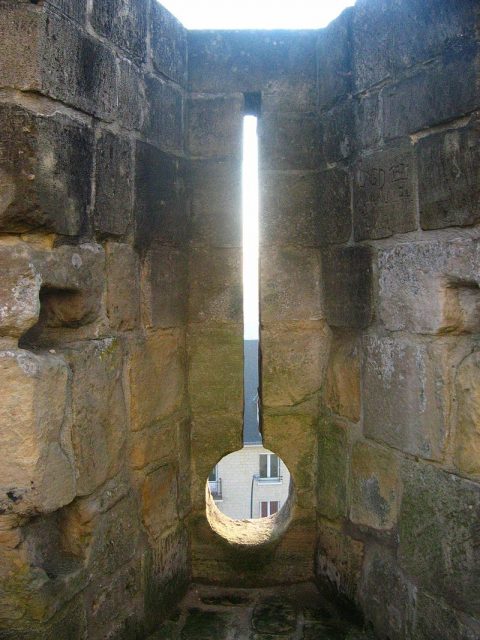 A loophole (or an inverted keyhole embrasure) at the Château de Caen, France. Such holes enabled castle defenders to fire both arrows and cannon projectiles. Photo by Urban CC BY-SA 3.0