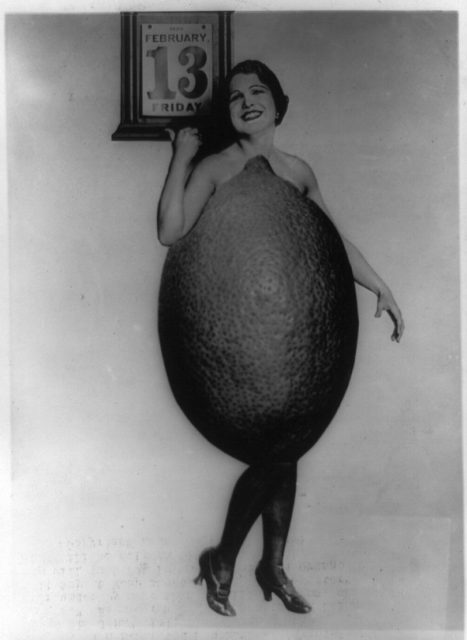Miss Rose Cade, Queen of the Lemons, who was also nominated Southern California’s “Swat the Jinx” girl, dressed in a model of a large lemon pointing to Friday, February 13, 1920.