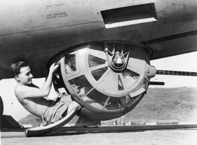 A crewman poses with the Sperry ball turret of a Royal Air Force B-24, Burma, c.1943-1945.