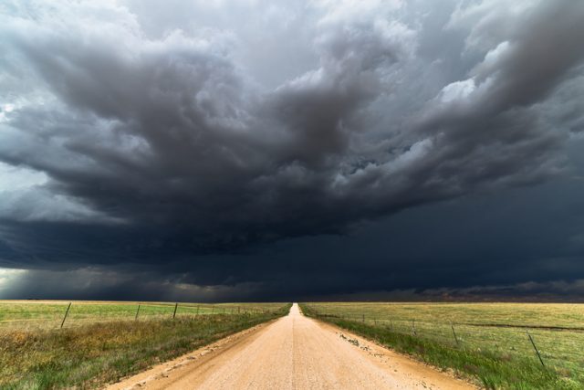 Dark storm clouds on a deserted dirt road. Many people had to flee their homes due to the ravages caused by the summerless year.