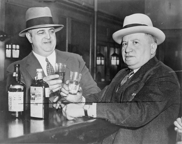 Izzy Einstein and Moe Smith, former police officers during Prohibition, sharing a toast in a New York Bar.