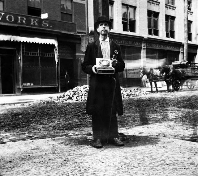 A blind man stands alone on a street corner, offering pencils for sale in New York City, 1890.