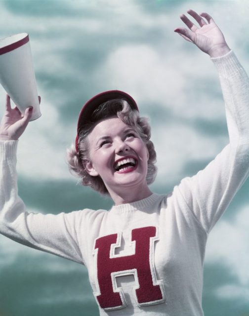 Smiling teen girl cheerleader wearing varsity letter sweater, Los Angeles, California, 1949. Photo by Camerique/Getty Images