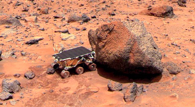 Sojourner rover taking an Alpha Proton X-ray Spectrometer measurement of Yogi. Pathfinder mission – Mars exploration – NASA.