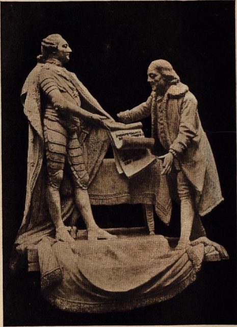 Picture of a statue of King Louis XVI of France and Benjamin Franklin signing the Treaty of Alliance.