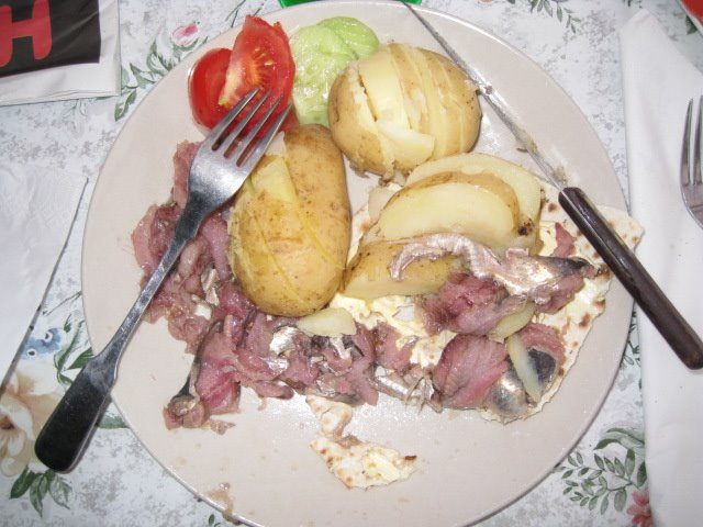 Surströmming served on flatbread with boiled potatoes and salad.