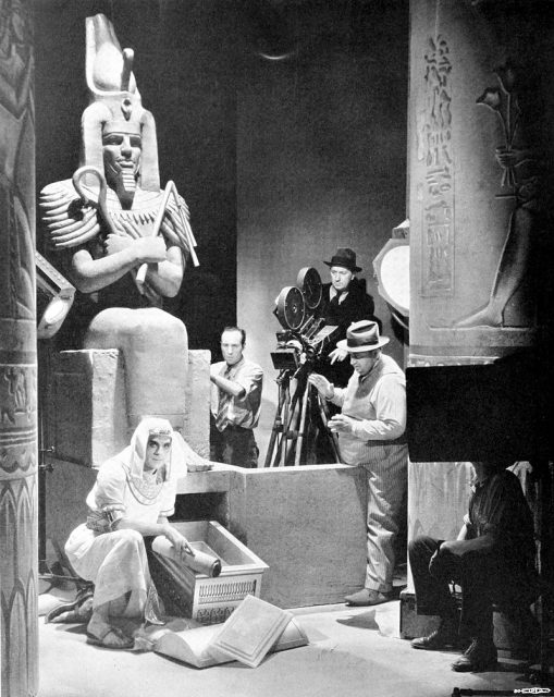 Photograph of Karl Freund directing Boris Karloff on the set of The Mummy. Caption reads as follows: Here is Karl Freund, long time cameraman and now director, following Boris Karloff in his character in Universal’s “Im-ho-tep,” with Charles Stumar at the camera. Photographed by Fred R. Archer.