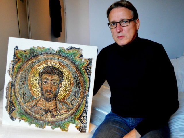 Arthur Brand poses with the missing mosaic of St Mark, a rare piece of stolen Byzantine art from Cyprus, in a hotel room in The Hague on November 17, 2018. – Brand said he handed back the artwork to Cypriot authorities on the same day. (Photo by Jan HENNOP / AFP)