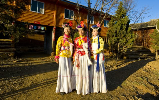 Lugu Lake, Sichuan Province, China – March 03, 2011: Three Mosuo tribe girls in traditional costume at sunset in Lugu Lake, Sichuan Province, China.