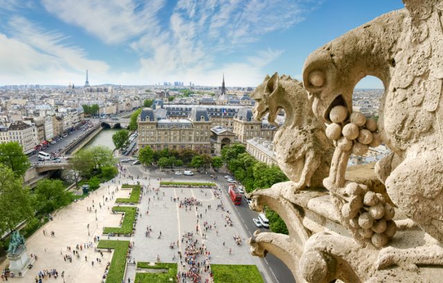 Top view of Paris from the tower of the Cathedral Notre-Dame de Paris with the gargoyles on the foreground against of sky with clouds