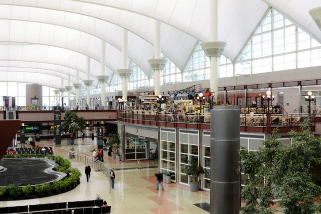 Denver International Airport interior with travelers, shops and restaurants. The teflon-coated fiberglass roof is one of the major architecture features.