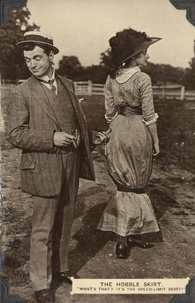 A postcard (c.1911) depicting a man and a women dressed in the fashion of the era. Caption: The Hobble Skirt “What’s that? It’s the speed-limit skirt!”