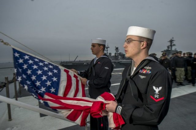 The United States flag is lowered to half mast aboard USS George H.W. Bush on December 1, 2018.