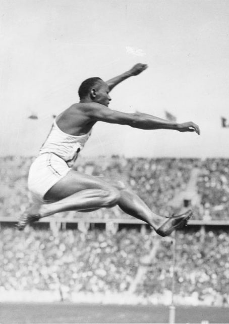 Jesse Owens with his record-setting long jump, wearing Dasslers’ shoes, at the 1936 Berlin Olympics. Photo by Bundesarchiv, Bild 183-R96374 / CC-BY-SA 3.0