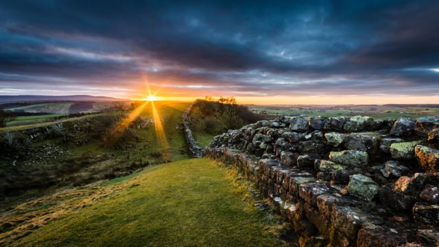 Hadrian’s Wall on Walltown Crags at sunset with dramatic clouds.