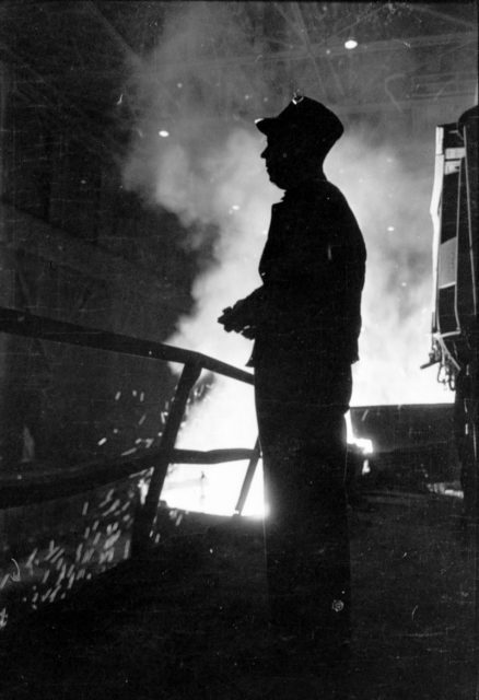 Steel worker standing in mill with smelter in the background, in Chicago, Illinois, 1949. Image from Look photographic assignment ‘Chicago City of Contrasts’ by S. Kubrick.