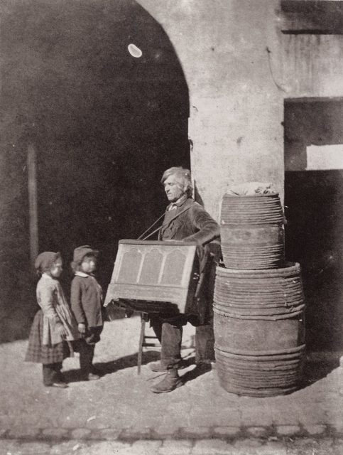 Le joueur d’orgue de barbarie et deux enfants (The Barrel Organ Player With Two Children Listening). Photograph taken by Charles Nègre in the backyard of his workshop at 21 Quai de Bourbon, on the Île Saint-Louis in Paris, circa 1853.