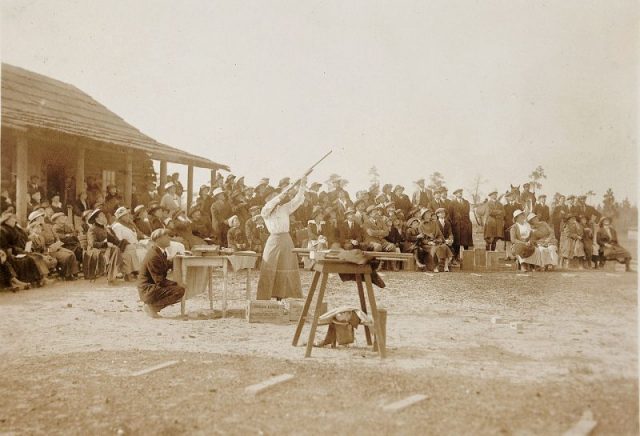 Annie Oakley shooting a shotgun in front of dozens of spectators. Pinehurst, NC