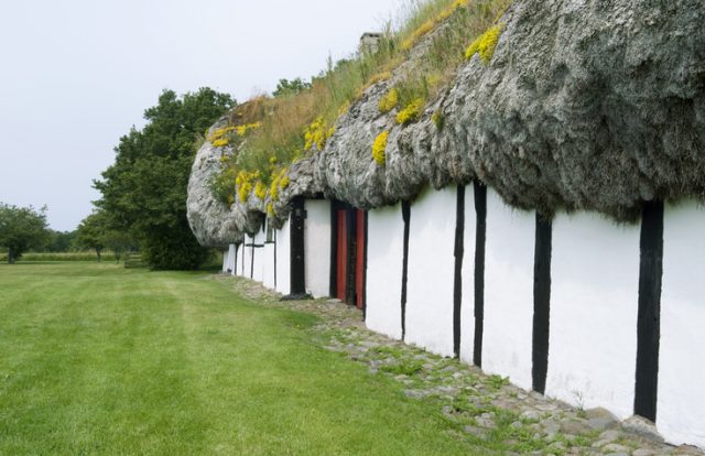 View along the exterior wall of an old half-timbered farmhouse thatched with a seaweed roof on the Kattegat island of Laesoe in July 2015
