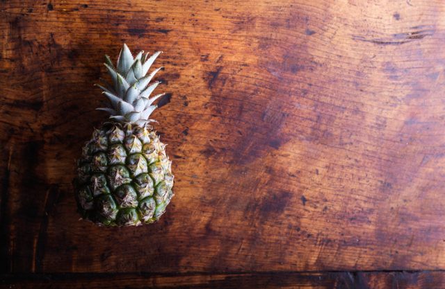 Fresh ripe pineapple laid on a table. Studio shot on wooden background.