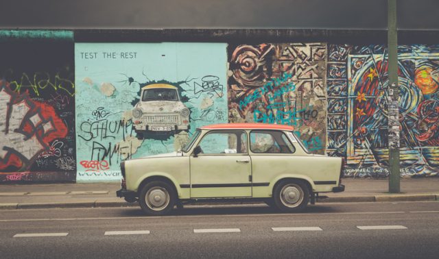 Berlin, Germany – July 12, 2015: Famous Berliner Mauer (Berlin Wall) at East Side Gallery with an old Trabant, the most common vehicle used in East Germany, in front, Berlin Friedrichshain-Kreuzberg, Germany.