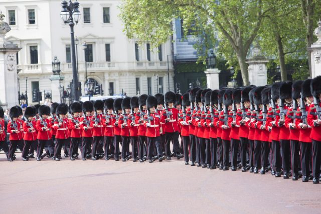 London, England – June 16, 2012: Heavily armed Queens Guard marching past Buckingham Palace as part of the Trooping the Colour ceremony