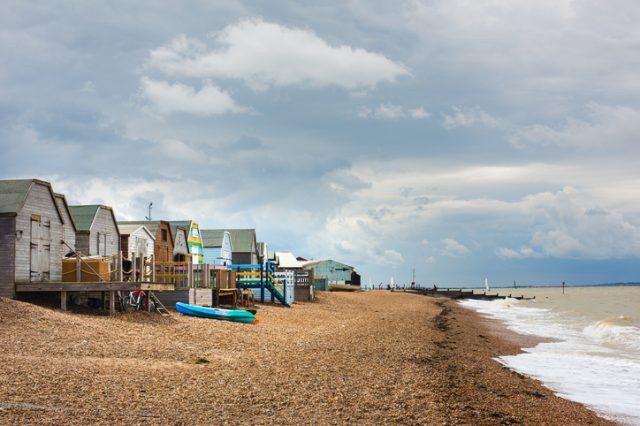 The sun on a cloudy day catches beach huts on the seafront in Whitstable, Kent