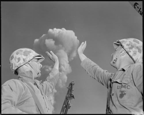 “U.S. soldiers pretending to touch a mushroom cloud created by a nuclear explosion in the Nevada desert, May 1952”