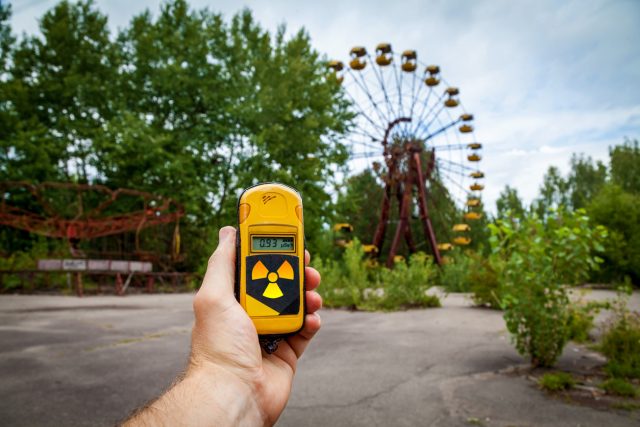 A dosimeter in hands with a level of radioactivity in an abandoned amusement park in the center of Pripyat, in the Chernobyl exclusion zone, Ukraine