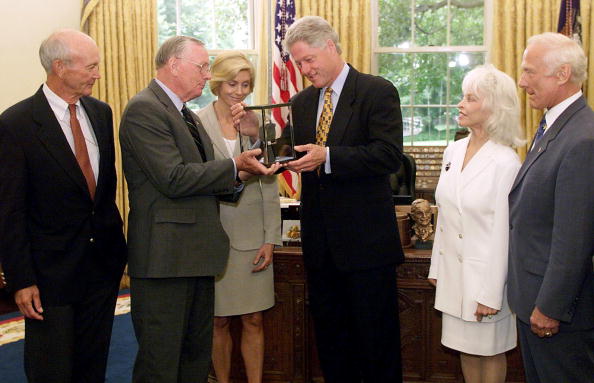 WASHINGTON, : US President Bill Clinton (C) is presented a rock from the moon by the original crew of Apollo 11 (L-R) Michael Collins, Neil Armstrong and his wife Carol Armstrong, Lois Aldrin and Buzz Aldrin 20 July, 1999, in the Oval office.  TIM SLOAN/AFP via Getty Images.