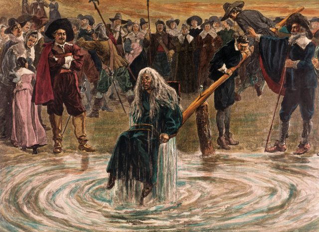 An accused witch going through the judgement trial, where she is dunked in water to prove her guilt of practicing witchcraft.