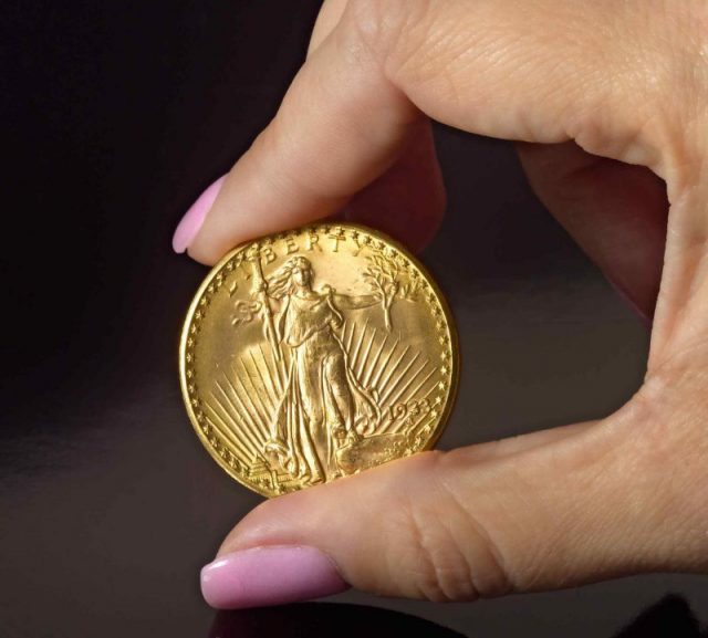 Person holding Double Eagle coin showing Liberty side