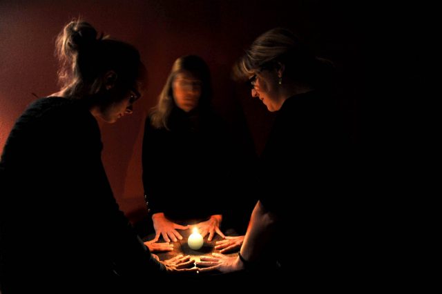Three women engaging in a seance