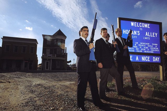 F.B.I. agents posing in front of the Hogan's Alley town sign