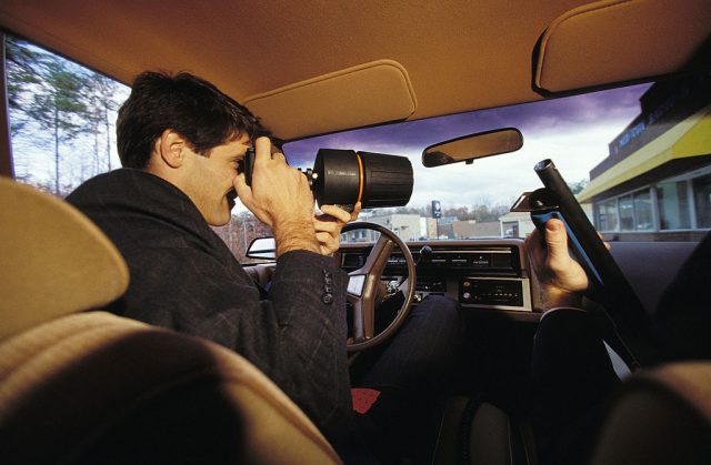 F.B.I. agent using a spyglass to look out of a car