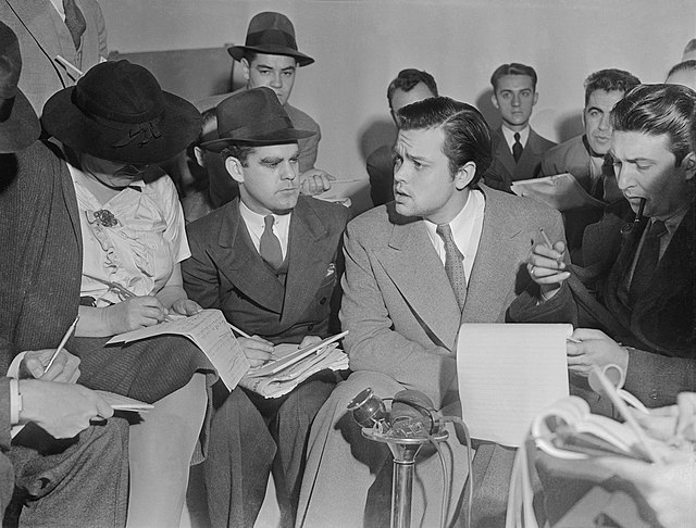 Orson Welles surrounded by reporters after the 1938 radio broadcast of The War of the Worlds