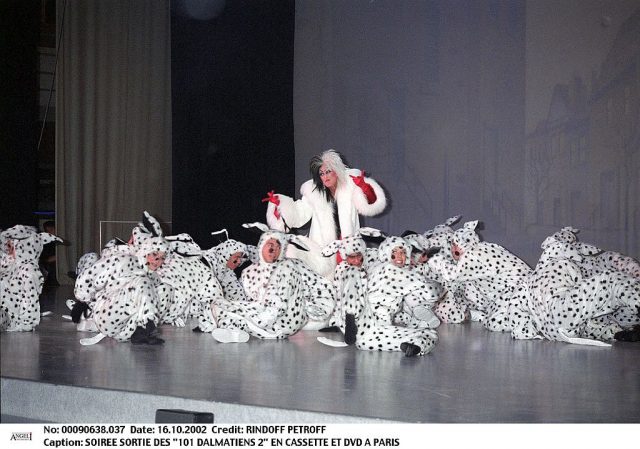 Cruella de Vil surrounded by humans dressed up as Dalmatians