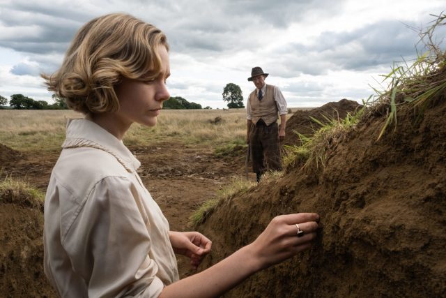 still from The Dig, showing Ralph Fiennes and a Sutton Hoo burial mound