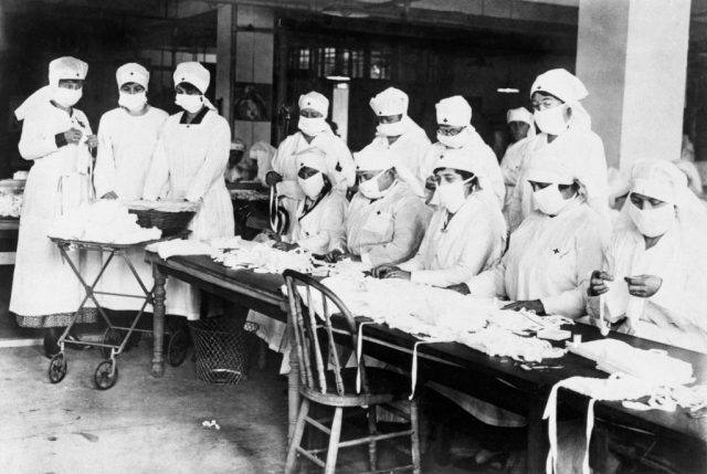 A group of women with the Red Cross making masks at a table