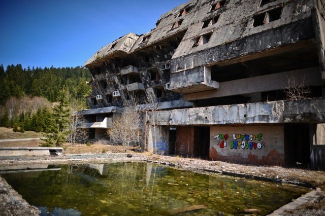Decrepit building with an algae-filled pool in the front